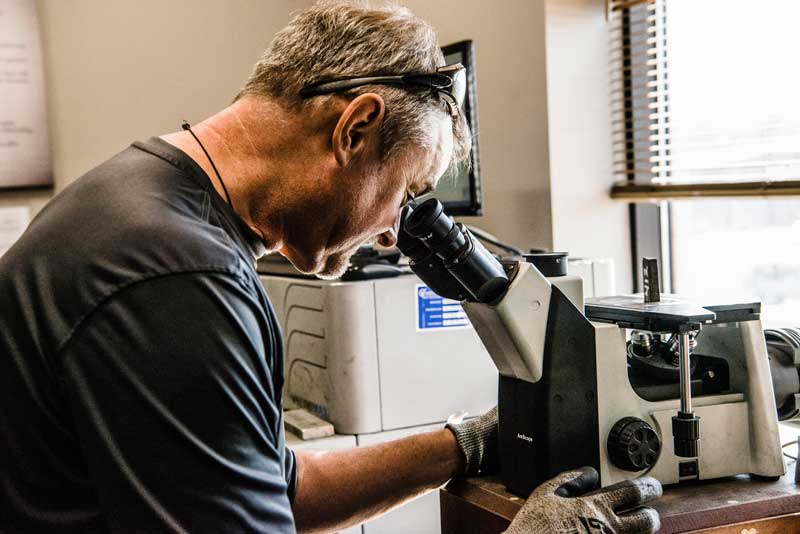 worker in the metallurgy lab looking through microscope